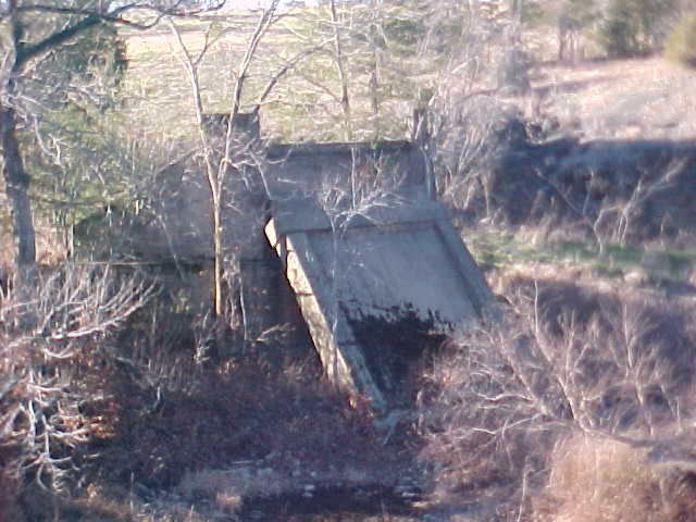 Abutment with pier leaning against it, taken from atop modern bridge