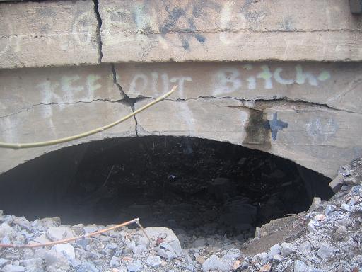 This tunnel is completely filled in with rocks and debris and also goes under the tracks. It's at the end of the dirt road you take to get to this place. If you look at google maps you can see that there used to be a road that went straight through here,